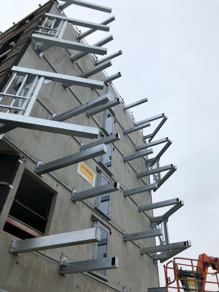Vue en contrebas des profils d'acier incorporés sur la façade du bâtiment pour la pose d'escaliers métalliques